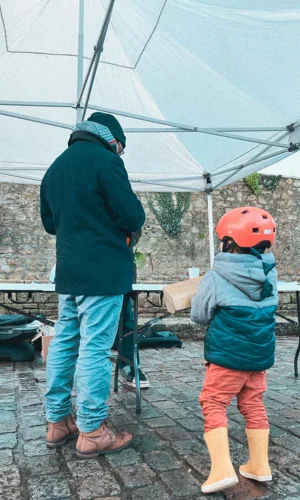 Jeune enfant qui pèse la bûche d'or pour le bûche challenge du bûche tour de Lorient Agglomération, organisé par les conseillers France Rénov' d'ALOEN